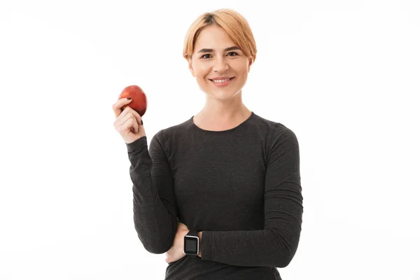 一个微笑的瑜伽女人的肖像穿着运动服装持有红苹果的白色背景 — 图库照片