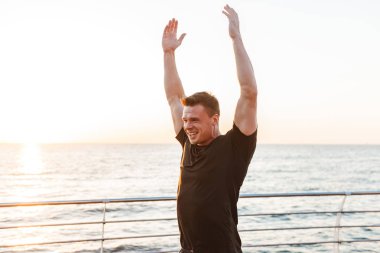 Deniz kenarında germe egzersizleri yapıyor heyecanlı genç sporcu