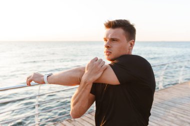 Deniz kenarında motive genç sporcu germe yapmak egzersizleri