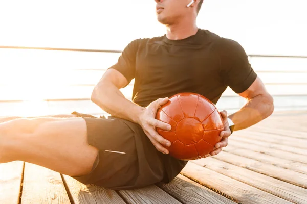 Обрезанное Изображение Молодого Человека Наушниках Делающего Упражнения Тяжелым Мячом Открытом — стоковое фото