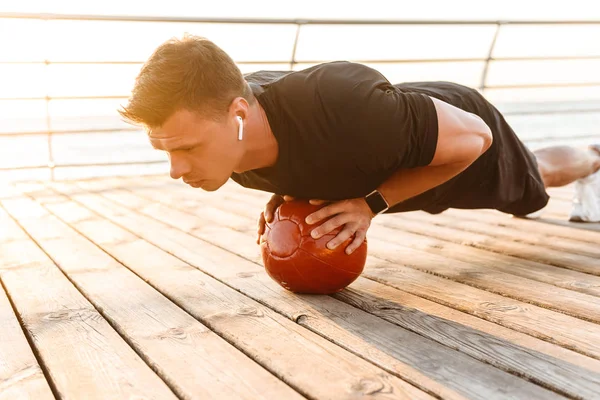 Sterke Jonge Sporter Oortelefoons Doen Oefeningen Met Een Zware Bal — Stockfoto