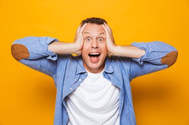 Çığlık ve sarı arka plan üzerinde izole kamera bakarak bir adam portresi şok bir orta yaşlı