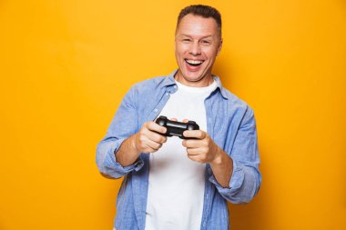 Duygusal adam sarı arka plan üzerinde izole fotoğrafı joystick ile oyun oynamak.