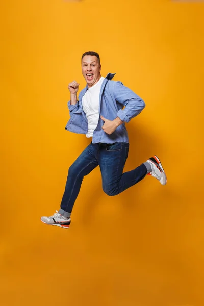 Image of emotional happy man jumping isolated over yellow background make thumbs up gesture.