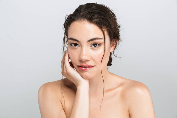 Beauty portrait of a smiling young topless woman with make up looking at camera isolated over gray background