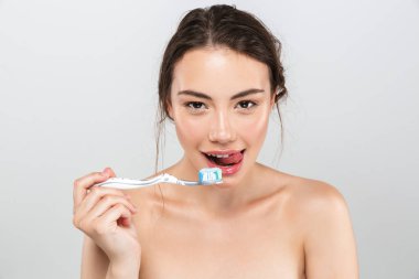 Kalıcı makyaj tutarak diş fırçası gri arka plan üzerinde izole diş macunu ile baştan çıkarıcı genç üstsüz kadın güzellik portresi