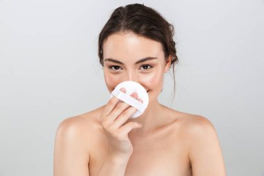 Gri arka plan üzerinde izole makyaj aplikatör ile hoş bir genç üstsüz kadın güzellik portresi