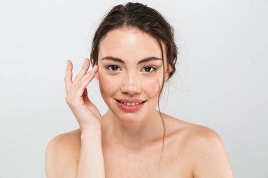 Kameraya bakarak makyaj ile gülümseyen genç üstsüz kadın güzellik portresi gri arka plan üzerinde izole