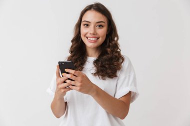 Cep telefonu beyaz arka plan üzerinde izole tutan bir gülümseyen genç casual esmer kadın portresi