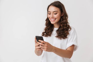 Cep telefonu beyaz arka plan üzerinde izole bakarak bir gülümseyen genç casual esmer kadın portresi