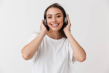 Beyaz arka plan üzerinde izole kulaklık ile müzik mutlu bir genç casual esmer kadın portresi
