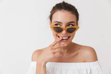 Uzak beyaz arka plan üzerinde izole bir neşeli genç casual esmer kadın seyir güneş gözlüğü portresi