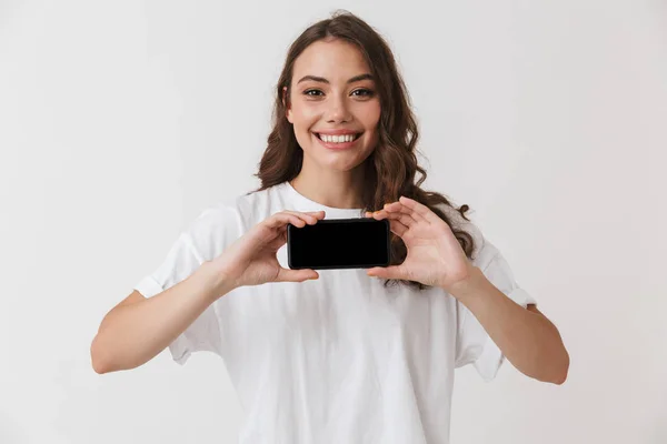 一个微笑的年轻的休闲黑发妇女的肖像显示空白屏幕移动电话在白色背景下隔离 — 图库照片