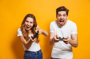 Duygusal genç adam ve birlikte oynama ve video oyunları üzerinde sarı arka plan izole joystick kullanarak yarışan kadın fotoğrafı