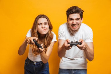 Gergin adam ve birlikte oynama ve video oyunları üzerinde sarı arka plan izole joystick kullanarak yarışan kadın heyecan