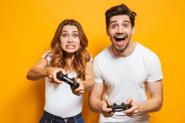 Neşeli adam ve memnun kadın birlikte izole sarı arka plan üzerinde joystick ile video oyunları oynarken görüntü