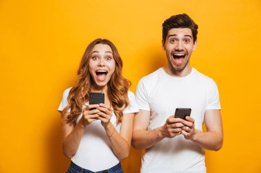Beyaz güzel insanlar adam fotoğrafı ve çığlık, her ikisi de kadın kullanarak akıllı telefonlar üzerinde sarı arka plan izole