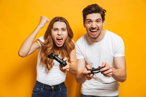 恍惚とした若い男と黄色背景に分離されたジョイスティックで一緒にビデオゲームを遊んで女のイメージ — ストック写真