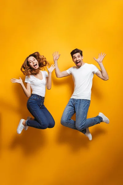幸せな若いカップル ジャンプし 拳を噛みしめながら驚きの叫び声の完全な長さの写真のように黄色の背景に分離された受賞者 — ストック写真