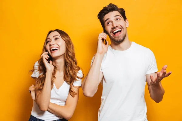 Alegre Jovem Casal Falando Telefones Celulares Isolados Sobre Fundo Amarelo — Fotografia de Stock