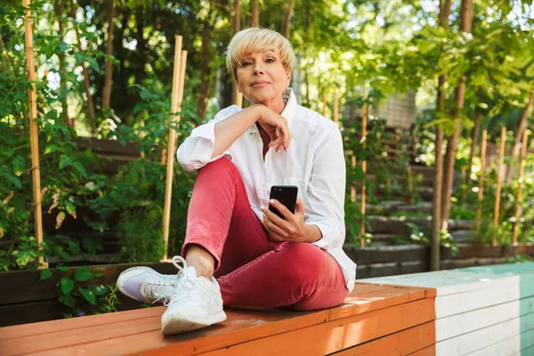 Mulher Madura Adorável Usando Telefone Celular Enquanto Descansa Parque — Fotografia de Stock