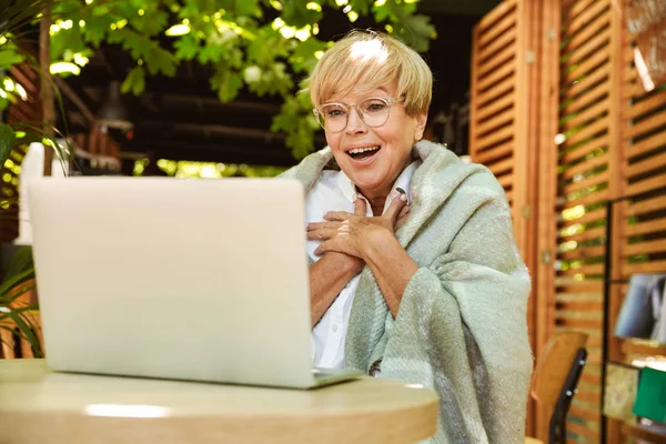 Возбужденная Зрелая Женщина Завернутая Одеяло Сидит Кафе Ноутбуком — стоковое фото