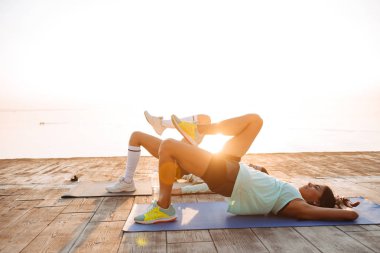 Görüntü şaşırtıcı genç iki spor kadın arkadaşlar açık havada sahilde yapmak spor egzersizleri.