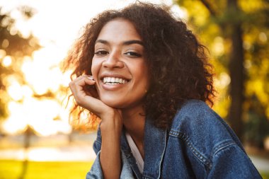 Genç ve güzel Afrikalı kız parkta iyi vakit denim ceket içinde