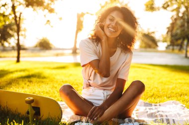 Mutlu genç Afrikalı kadın açık havada kaykay parkı çim üzerinde görüntü.