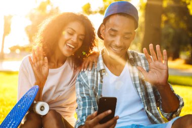 Bir selfie birlikte parkta alarak kaykaylar ile neşeli bir genç Afrikalı çift portresi