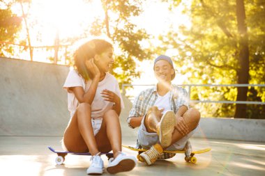 Kaykay birlikte paten parkta oturan ile gülen genç bir Afrikalı çift portresi