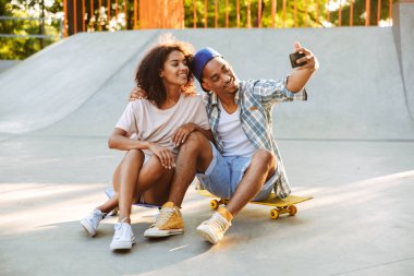 Bir selfie birlikte paten parkta alarak kaykaylar ile mutlu bir genç Afrikalı çift portresi