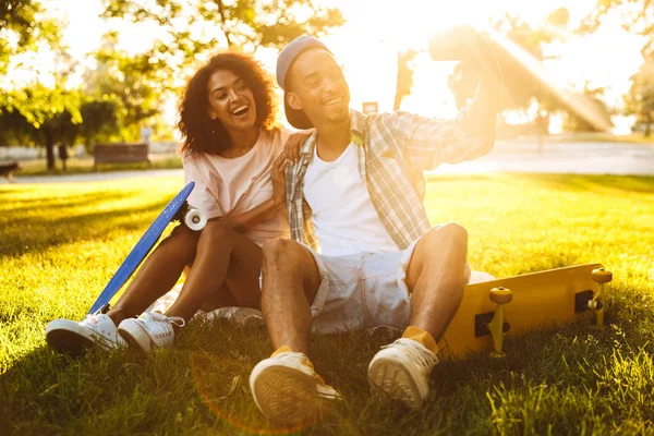 一个快乐的年轻非洲夫妇的肖像与滑板一起在公园自拍一起 — 图库照片