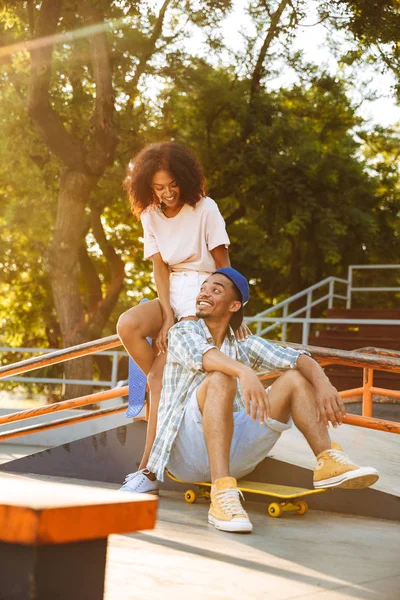 Portret Van Een Lachende Jonge Afrikaanse Paar Met Skateboards Zitten — Stockfoto