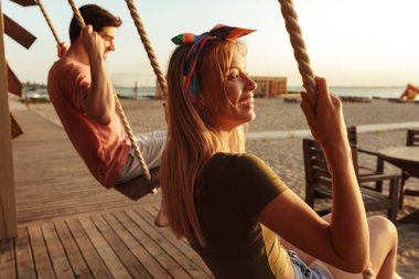 Arkadaşlar açık havada salıncakta sürme sahilde resmini.