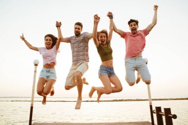 Grup dört arkadaşıyla kumsalda açık havada atlama çiftler sevgi dolu fotoğraf.