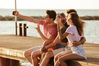 Açık havada sahilde oturan arkadaş grubu görüntüsünü almak bir selfie.