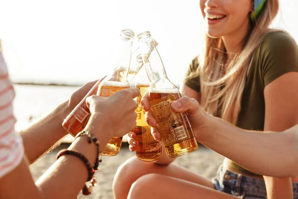 一群兴高采烈的朋友身着夏日服装 在海滩上用啤酒瓶敬酒 — 图库照片