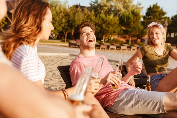 一群开朗的朋友穿着夏天的衣服喝啤酒 而在海滩放松 — 图库照片