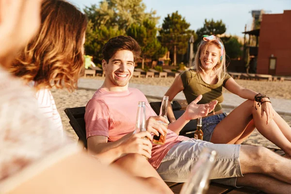 一群快乐的朋友穿着夏天的衣服喝啤酒 而在海滩放松 — 图库照片