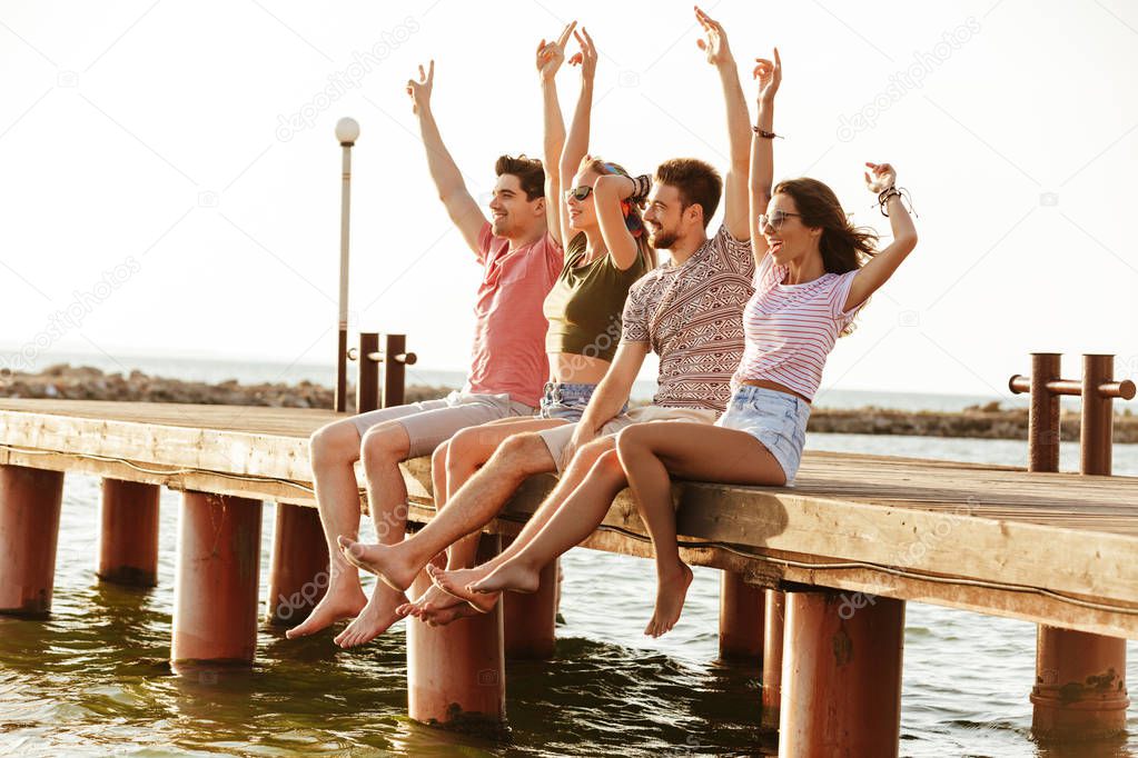 Picture of group of four friends loving couples sitting outdoors on the beach.