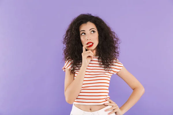 夏服上向きに見て スタジオで紫色の背景に分離した指をかむの巻き毛の美しい若い女性の写真 — ストック写真