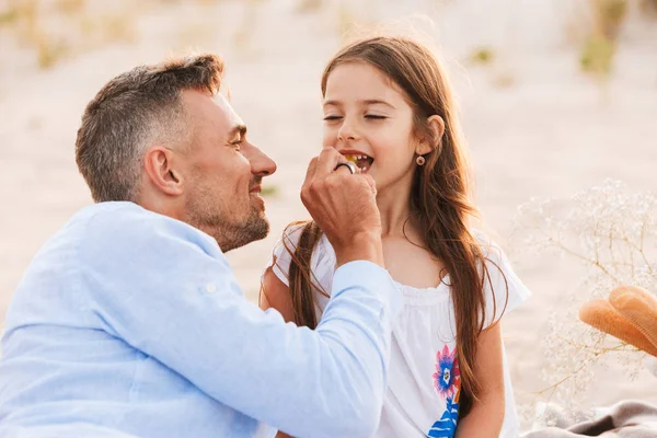 父と幼い娘がビーチでピクニックを持つ美しい家族 — ストック写真