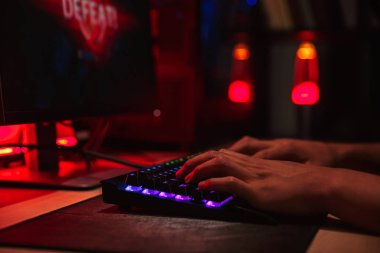 El oyun gencin karanlık odada arkadan aydınlatmalı renkli klavye kullanarak bilgisayarda video oyunları oynarken kaybetme