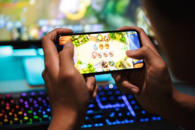 El oyun çocuk 16-18 akıllı telefon ve bilgisayar kulaklıklar giyen ve sırt rainbow klavye kullanarak karanlık odada video oyunları oynamak