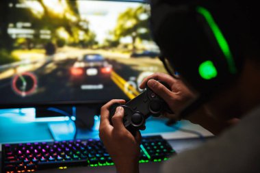 Genç oyun adam bilgisayarda kulaklık mikrofon ile giyen ve joystick kullanarak karanlık odada video oyunları oynarken closeup fotoğraf