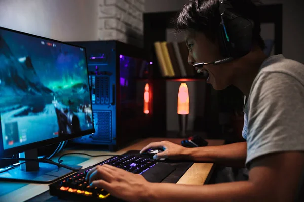 Gamer transmitindo o jogo de tiro em primeira pessoa enquanto explica a  jogabilidade aos assinantes enquanto está sentado na cadeira de jogos.  homem usando a configuração do pc jogando jogo de ação