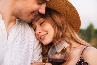 Genç tatlı sevgi dolu çift bardak şarap açık havada tutan.