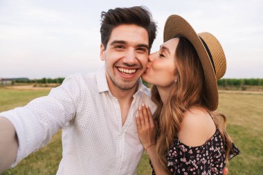 Genç mutlu tatlı sevgi dolu çift açık havada birbirleriyle sarılma resim çekmek bir selfie Kamera öpüşme.