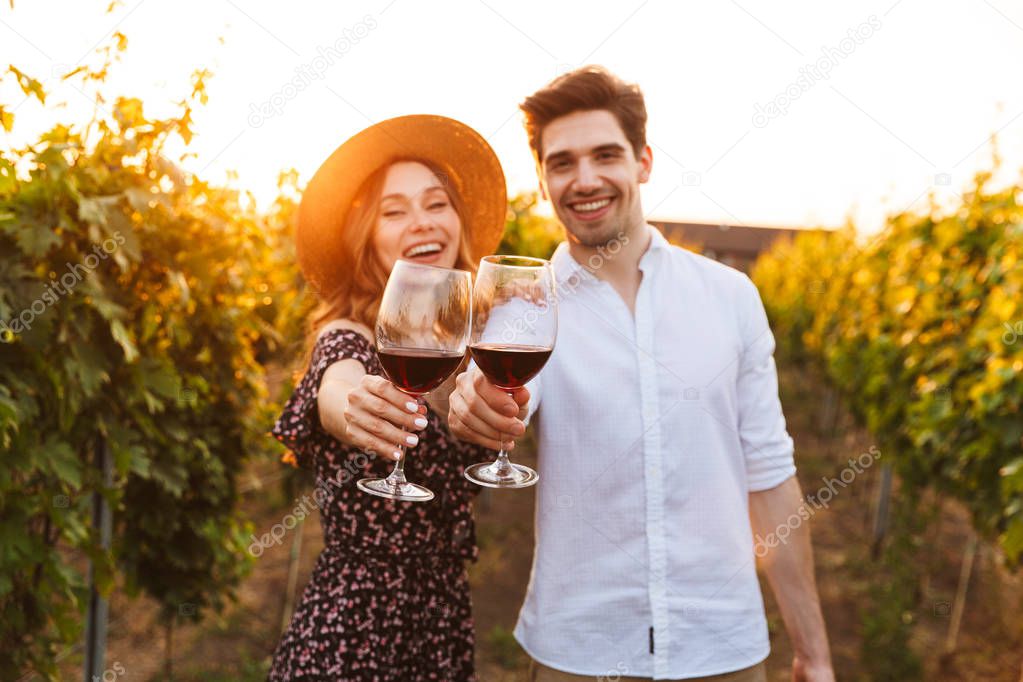 Photo of young cute happy loving couple outdoors drinking wine looking camera.